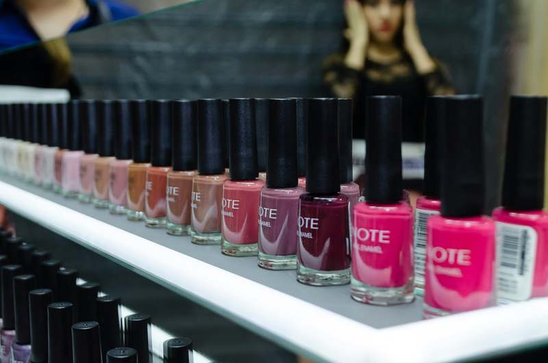 Close-up of diverse hands applying clear top coat on manicured nails